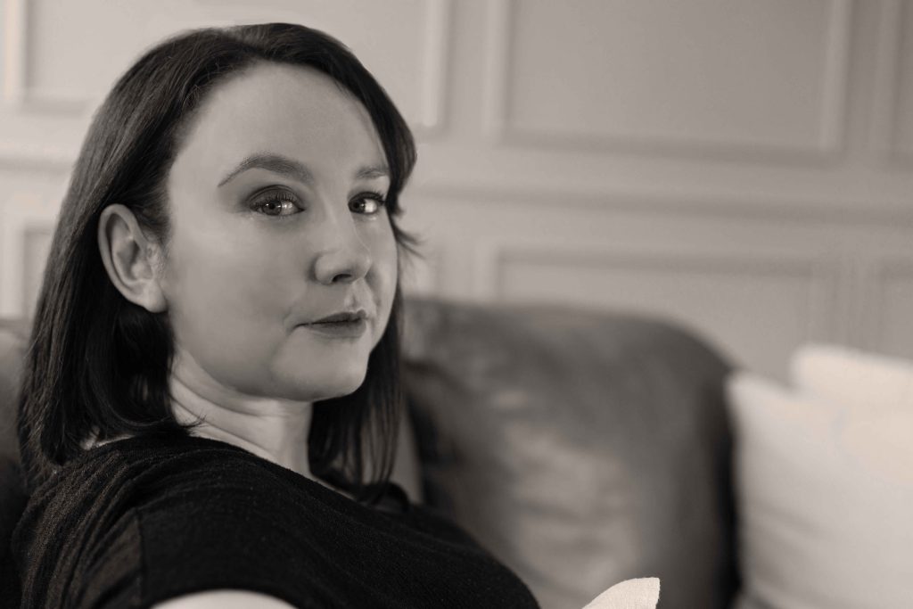 a close up black and white photo of Carmel Rice sitting on a sofa