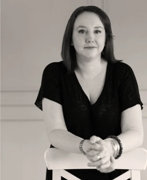 a black and white photo of Carmel Rice leaning on a chair